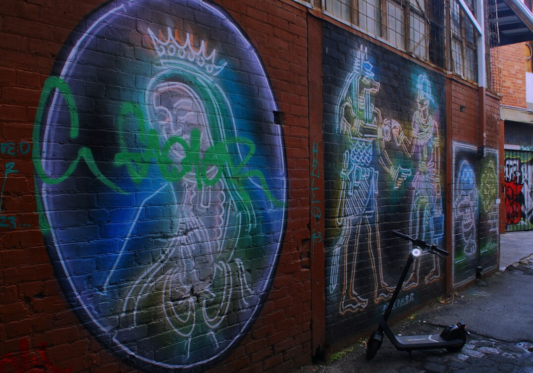 Community mural painted on a brick wall in a city alley